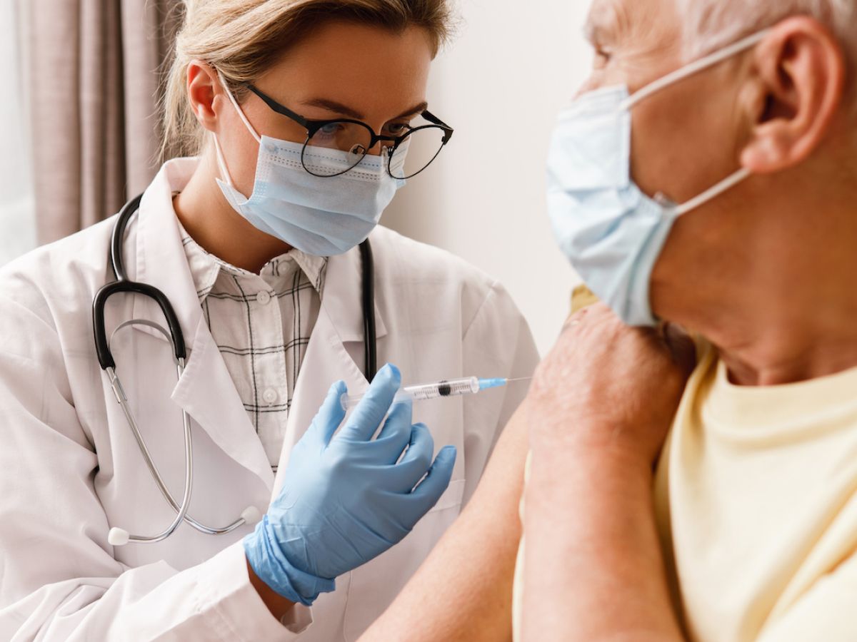 Doktorin impft älteren Patienten